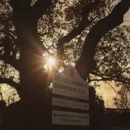 Sunlight breaks through the clouds just above the St Columba's Derryvolgie entrance sign