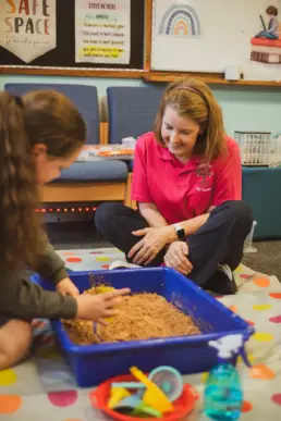 Child using sensory materials during a play therapy session supported by a therapist.